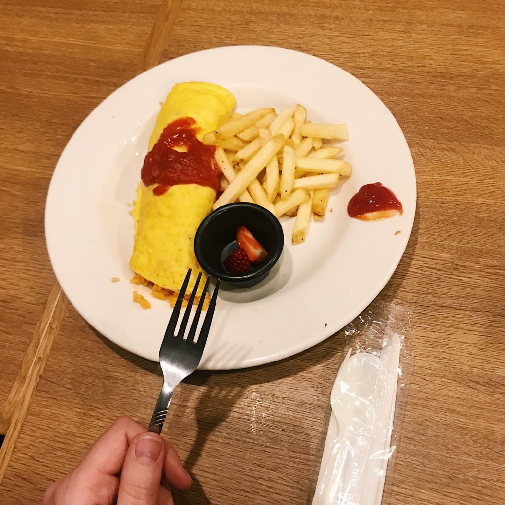 plate of french fries and egg omelette with plastic and metal silverware