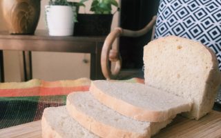 sliced white bread sitting on cutting board with plants and chair in background