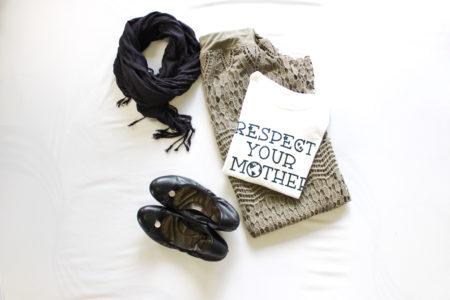 green skirt with white t-shirt that says "respect your mother" with black scarf and black ballet flats on white surface