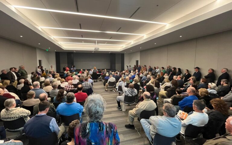 crowded room full of people sitting down facing the front of the auditorium